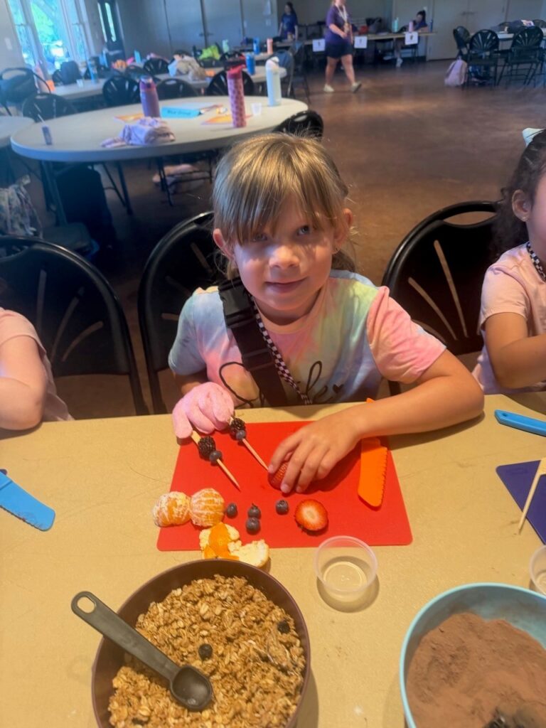 Elizabeth prepares a healthy fruit snack during a nutrition activity at Little Shots Camp.
