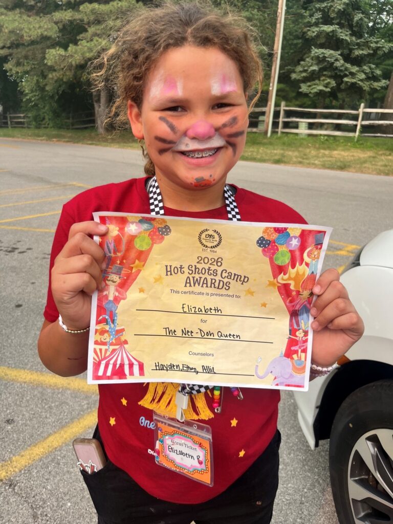 Elizabeth smiles while holding her Hot Shots Camp Award certificate at the end of camp.