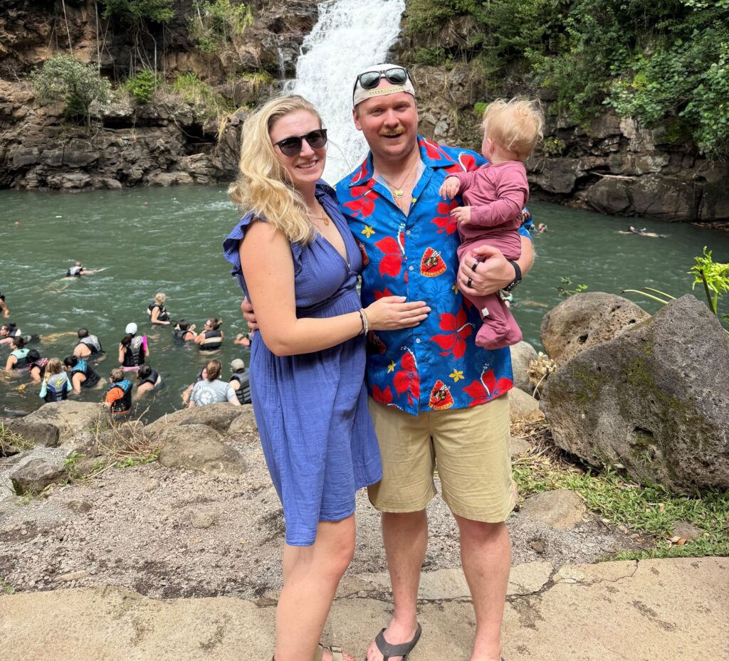 Michael and Amanda Johnson standing with their daughter, Adeline, in front of a waterfall.