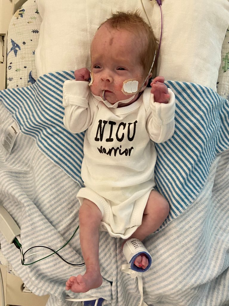 Jaxson Bruce resting in the NICU wearing a NICU Warrior onesie