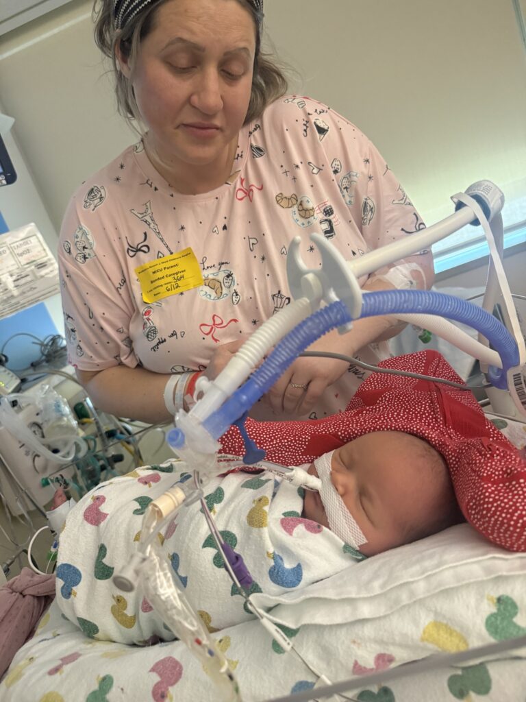 Jamie McMillan beside Joslyn as she receives respiratory support in the NICU