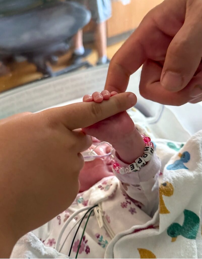 Sophie Stephens holds a family member's finger during her NICU stay